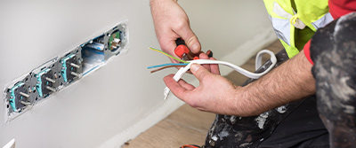 An electrician rewiring a plug socket